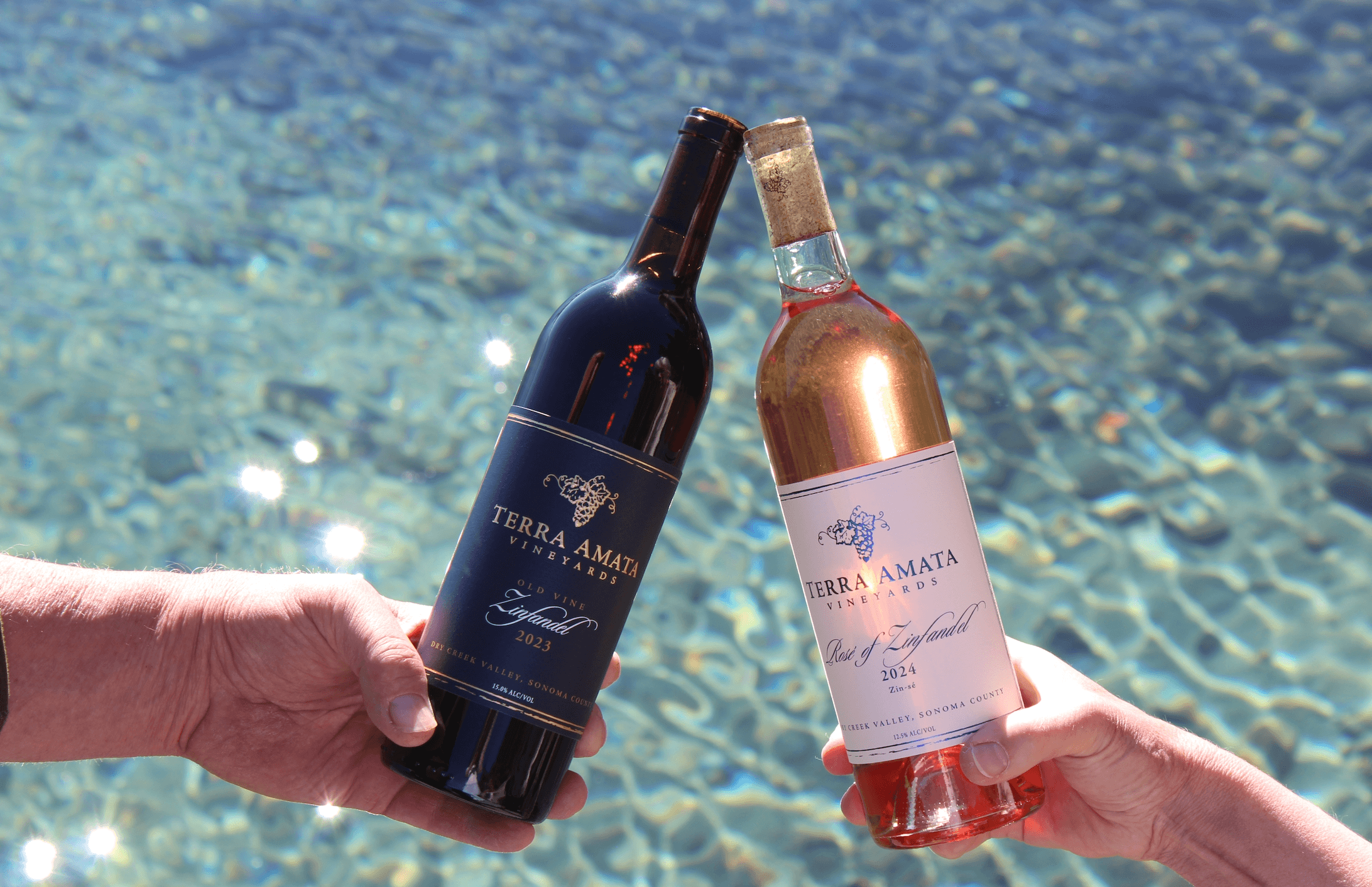 two wine bottles held over reflective water